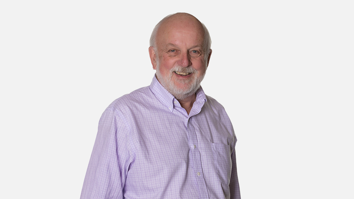 Person with white beard and in purple shirt smiling